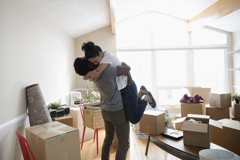 Enthousiaste, couple affectueux, étreignant dans une nouvelle maison, déballant des boîtes en carton