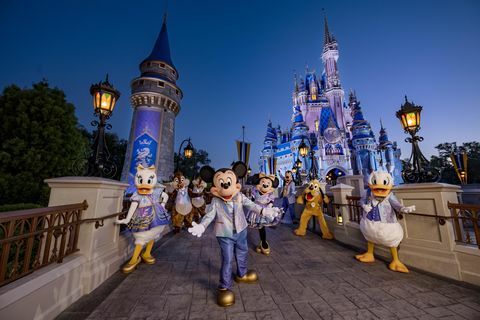 mickey mouse et ses amis portant leurs vêtements scintillants du 50e anniversaire tout en posant devant le château de cendrillon au parc du royaume magique