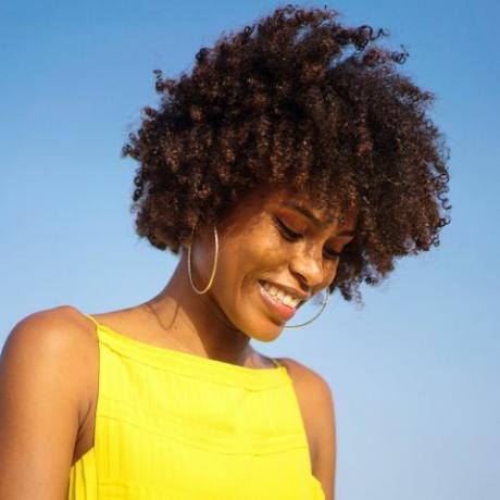 portrait d'une jeune femme noire vêtue d'une robe jaune souriante